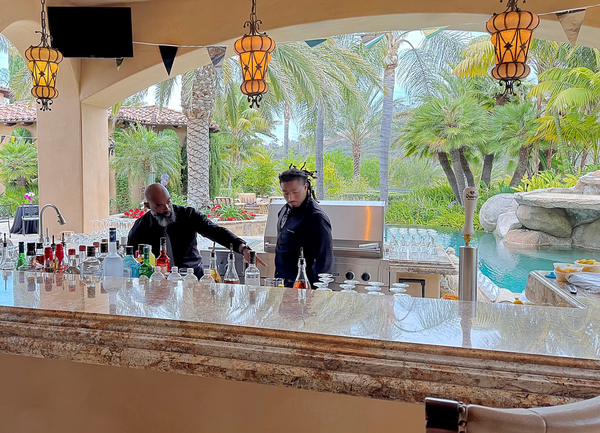Upscale poolside estate bar with two professional bartenders for hire serving craft cocktails at a private luxury event